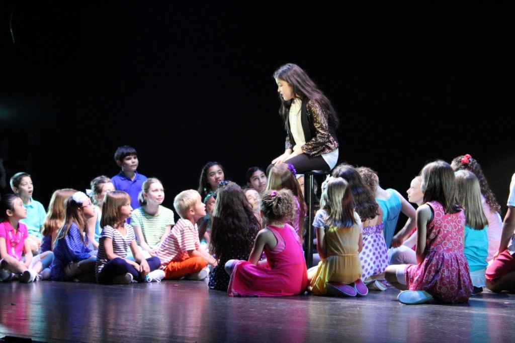 Joseph and the Amazing Technicolor Dreamcoat - kids sitting on stage