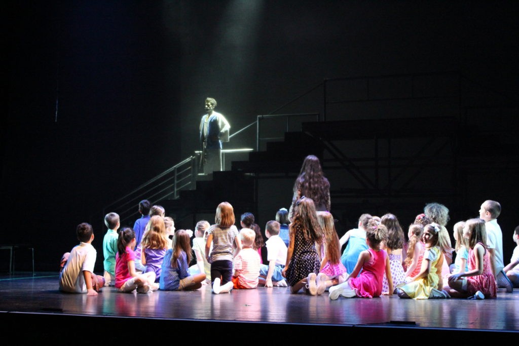 Joseph and the Amazing Technicolor Dreamcoat - kids sitting on stage