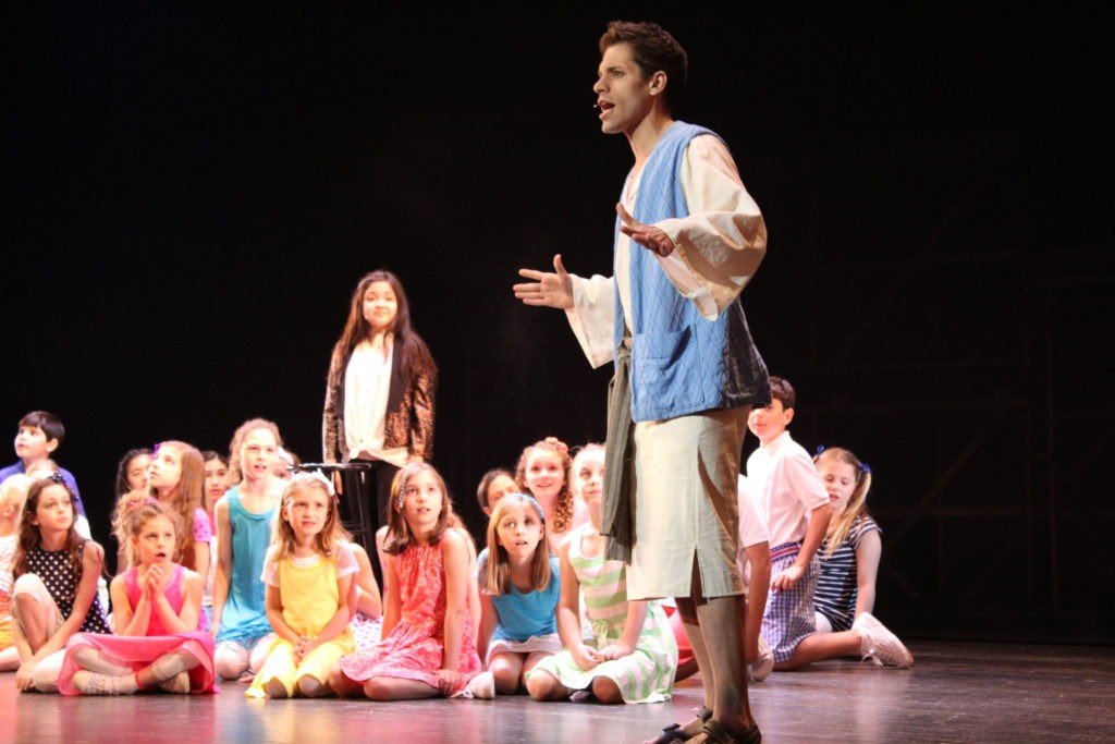 Joseph and the Amazing Technicolor Dreamcoat - kids sitting on stage with joseph in regular garb