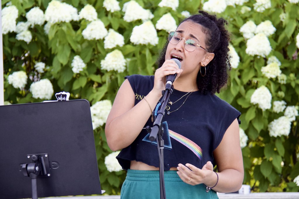 sabrina genesis singing in front of flowers