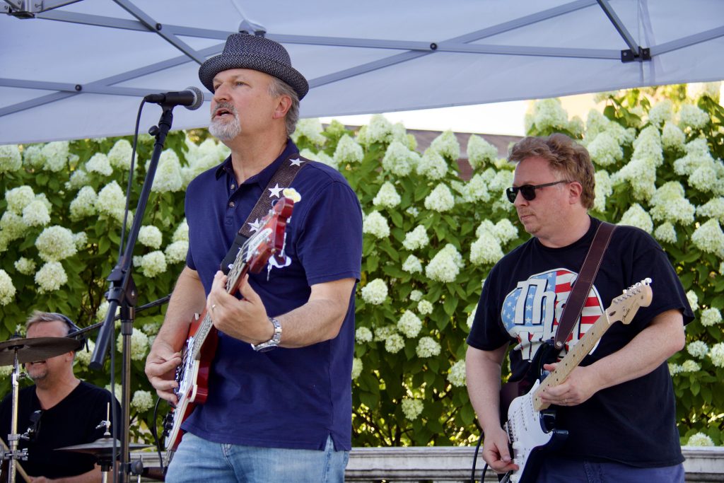 guitarist ans bassist performing in front of flower bush